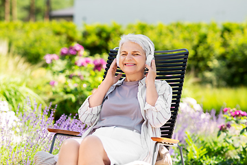 Image showing happy senior woman with headphones at garden