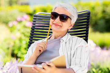 Image showing happy senior woman with diary at summer garden