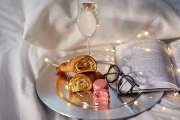 Image showing champagne, croissants, book and glasses in bed