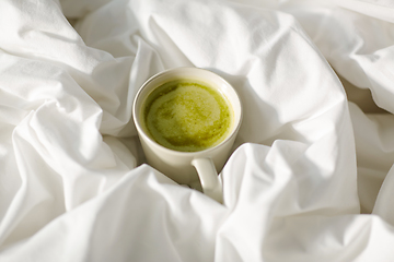 Image showing cup of matcha tea in bed at home