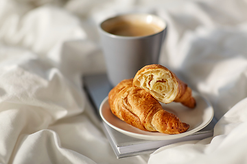 Image showing croissants, cup of coffee and book in bed at home