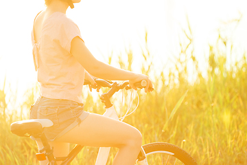 Image showing Joyful young woman riding a bicycle at the riverside and meadow promenade