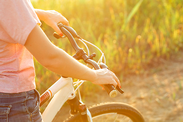 Image showing Joyful young woman riding a bicycle at the riverside and meadow promenade