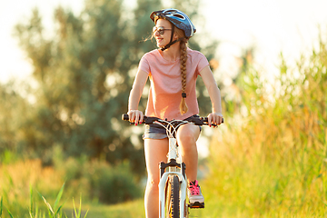 Image showing Joyful young woman riding a bicycle at the riverside and meadow promenade