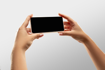 Image showing Close up female hands holding smartphone with blank screen during online watching of popular sport matches and championships all around the world. Copyspace for ad