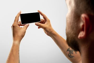 Image showing Close up male hands holding phone with blank screen during online watching of popular sport matches and championships all around the world. Copyspace for ad