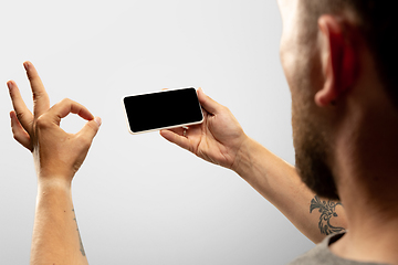 Image showing Close up male hands holding phone with blank screen during online watching of popular sport matches and championships all around the world. Copyspace for ad