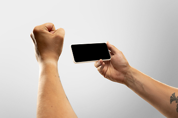 Image showing Close up male hands holding phone with blank screen during online watching of popular sport matches and championships all around the world. Copyspace for ad