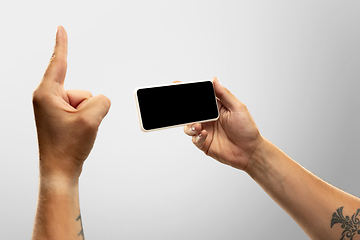 Image showing Close up male hands holding phone with blank screen during online watching of popular sport matches and championships all around the world. Copyspace for ad