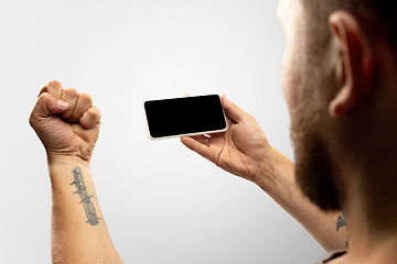 Image showing Close up male hands holding phone with blank screen during online watching of popular sport matches and championships all around the world. Copyspace for ad