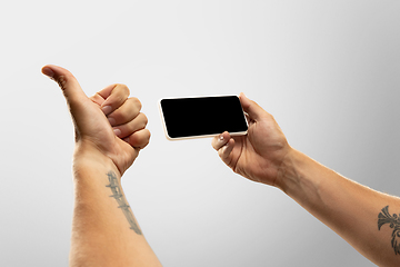 Image showing Close up male hands holding phone with blank screen during online watching of popular sport matches and championships all around the world. Copyspace for ad