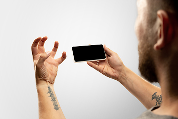 Image showing Close up male hands holding phone with blank screen during online watching of popular sport matches and championships all around the world. Copyspace for ad