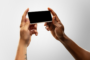Image showing Close up male hands holding phone with blank screen during online watching of popular sport matches and championships all around the world. Copyspace for ad