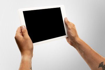 Image showing Close up male hands holding tablet with blank screen during online watching of popular sport matches and championships all around the world. Copyspace for ad