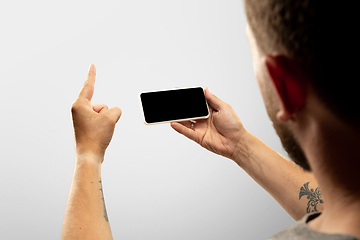 Image showing Close up male hands holding phone with blank screen during online watching of popular sport matches and championships all around the world. Copyspace for ad