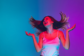 Image showing Caucasian young woman\'s portrait isolated on gradient purple-blue background in neon light, cinema, movie watching