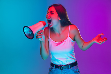 Image showing Caucasian young woman\'s portrait isolated on gradient purple-blue background in neon light, cinema, movie watching