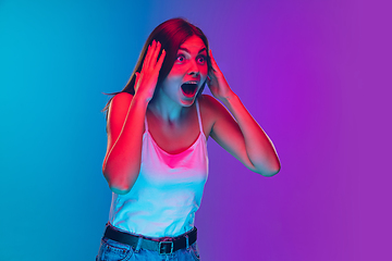 Image showing Caucasian young woman\'s portrait isolated on gradient purple-blue background in neon light, cinema, movie watching