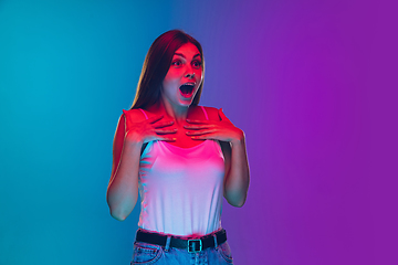 Image showing Caucasian young woman\'s portrait isolated on gradient purple-blue background in neon light, cinema, movie watching