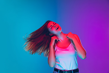 Image showing Caucasian young woman\'s portrait isolated on gradient purple-blue background in neon light, cinema, movie watching