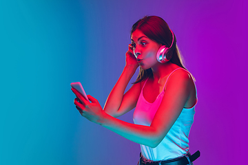 Image showing Caucasian young woman\'s portrait isolated on gradient purple-blue background in neon light