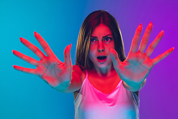 Image showing Caucasian young woman\'s portrait isolated on gradient purple-blue background in neon light, cinema, movie watching