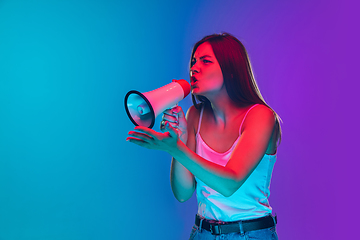 Image showing Caucasian young woman\'s portrait isolated on gradient purple-blue background in neon light, cinema, movie watching