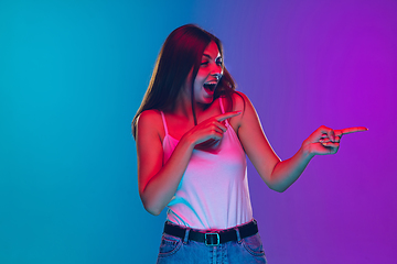 Image showing Caucasian young woman\'s portrait isolated on gradient purple-blue background in neon light, cinema, movie watching