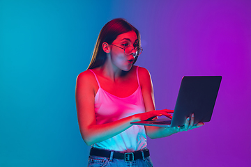 Image showing Caucasian young woman\'s portrait isolated on gradient purple-blue background in neon light, cinema, movie watching