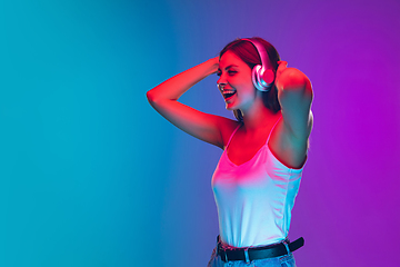 Image showing Caucasian young woman\'s portrait isolated on gradient purple-blue background in neon light