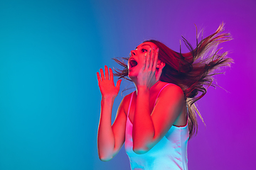 Image showing Caucasian young woman\'s portrait isolated on gradient purple-blue background in neon light, cinema, movie watching