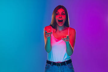 Image showing Caucasian young woman\'s portrait isolated on gradient purple-blue background in neon light, cinema, movie watching