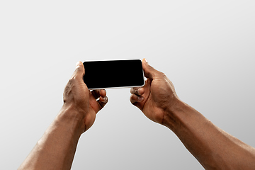 Image showing Close up male hands holding smartphone with blank screen during online watching of popular sport matches and championships all around the world. Copyspace for ad