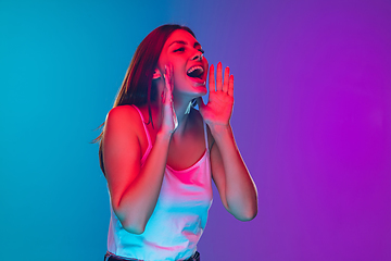 Image showing Caucasian young woman\'s portrait isolated on gradient purple-blue background in neon light, cinema, movie watching