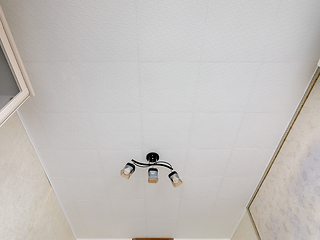 Image showing A fragment of the interior, a view of a modest ceiling with glued ceiling tiles and a small chandelier