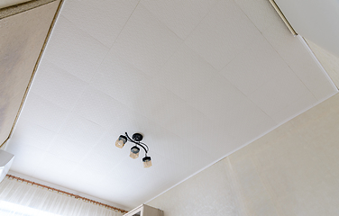 Image showing Modest ceiling with glued ceiling tiles and a small chandelier