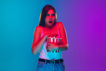 Image showing Caucasian young woman\'s portrait isolated on gradient purple-blue background in neon light, cinema, movie watching