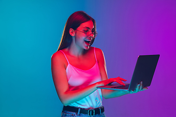 Image showing Caucasian young woman\'s portrait isolated on gradient purple-blue background in neon light, cinema, movie watching