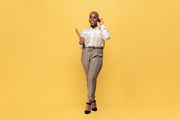 Image showing Young african-american woman in casual wear on yellow background. Bodypositive female character, plus size businesswoman