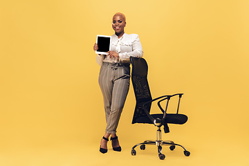 Image showing Young african-american woman in casual wear on yellow background. Bodypositive female character, plus size businesswoman