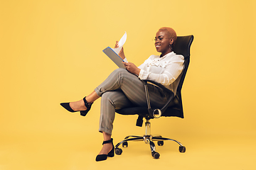 Image showing Young african-american woman in casual wear on yellow background. Bodypositive female character, plus size businesswoman