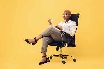 Image showing Young african-american woman in casual wear on yellow background. Bodypositive female character, plus size businesswoman