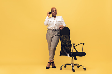 Image showing Young african-american woman in casual wear on yellow background. Bodypositive female character, plus size businesswoman