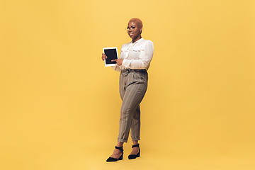 Image showing Young african-american woman in casual wear on yellow background. Bodypositive female character, plus size businesswoman