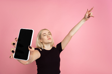 Image showing Portrait of young caucasian woman with bright emotions on coral pink studio background