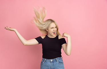 Image showing Portrait of young caucasian woman with bright emotions on coral pink studio background