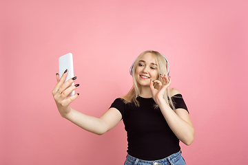 Image showing Portrait of young caucasian woman with bright emotions on coral pink studio background