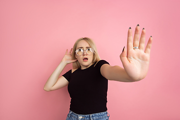 Image showing Portrait of young caucasian woman with bright emotions on coral pink studio background