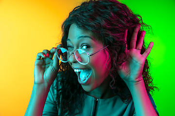 Image showing African-american young woman\'s portrait isolated on gradient yellow-green background in neon light