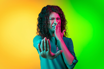 Image showing African-american young woman\'s portrait isolated on gradient yellow-green background in neon light